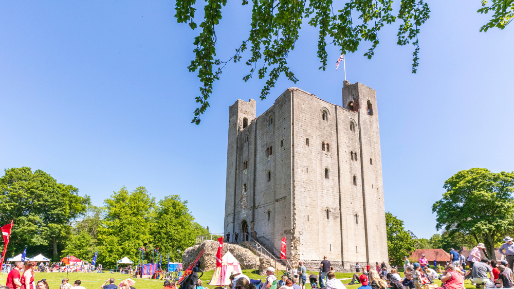 People sitting and watching a joust event at Hedingham Castle 